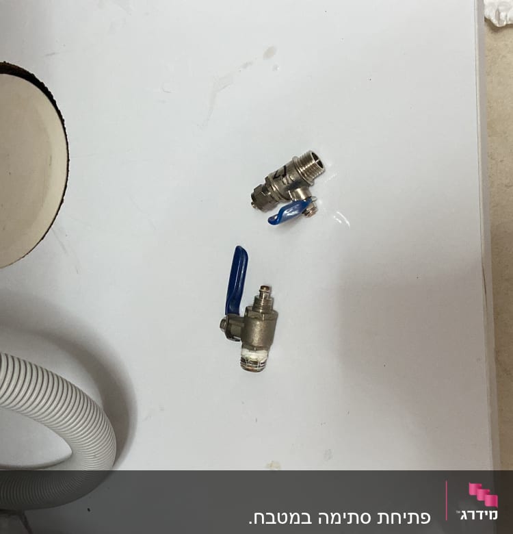 שני ברזי מים עם ידיות כחולות על משטח לבן